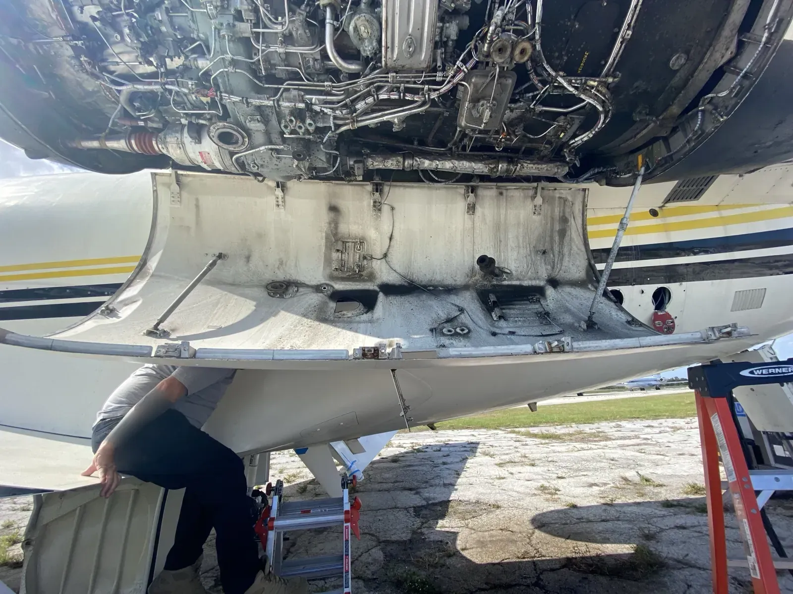 Engine cowling open under a business jet during an inspection