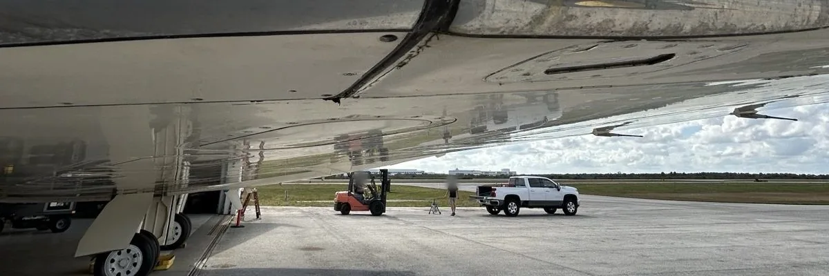 Business jet wing over the ramp outside a hangar